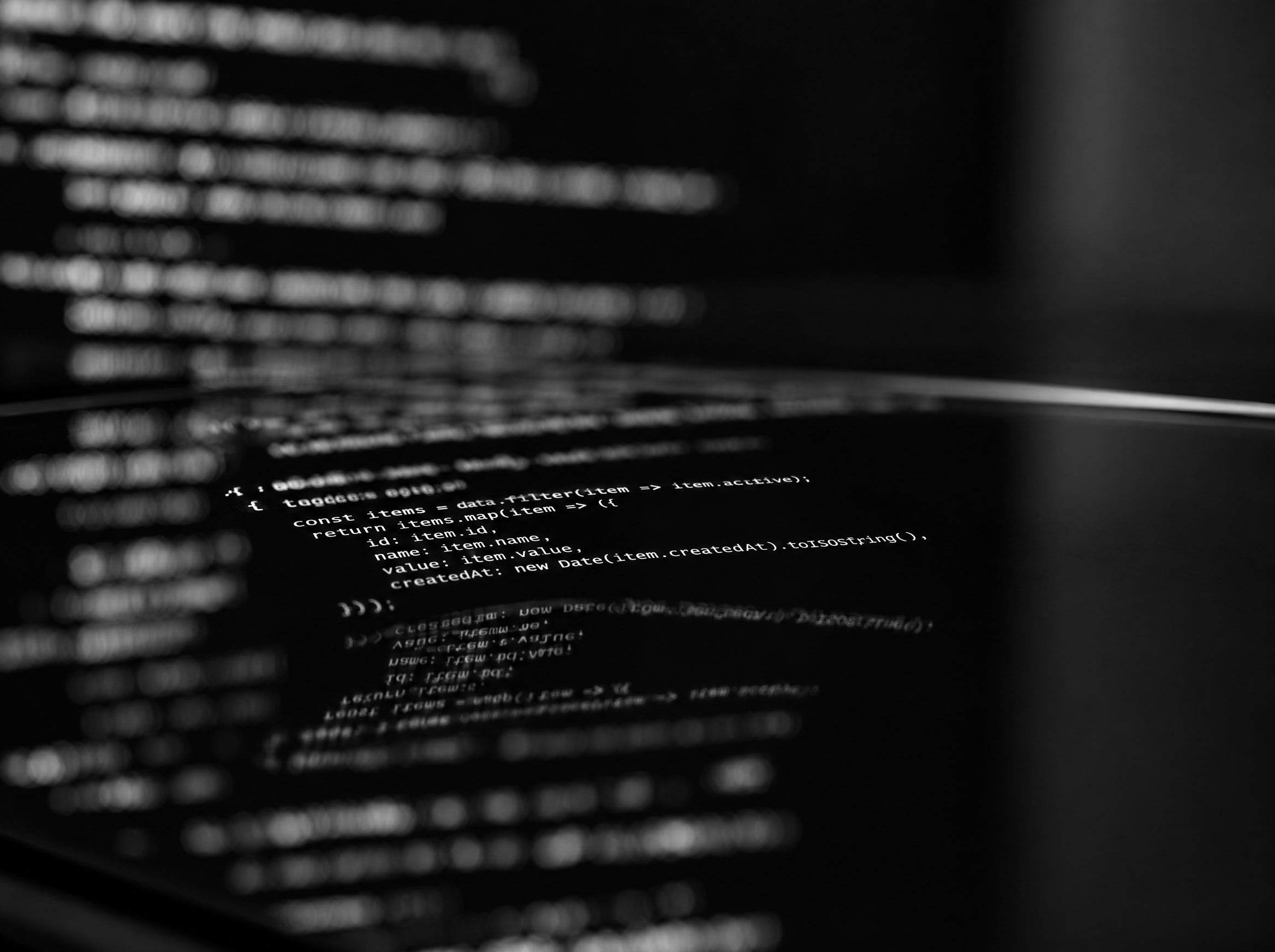 Source code reflected in black glass, mostly out of focus